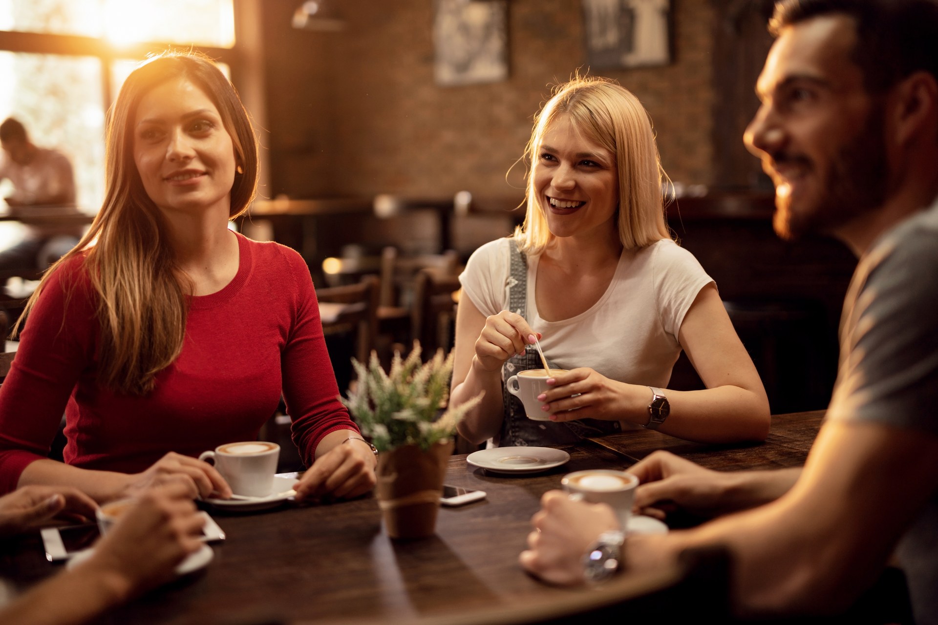 Troje przyjaciół rozmawia przy kawie w kawiarni