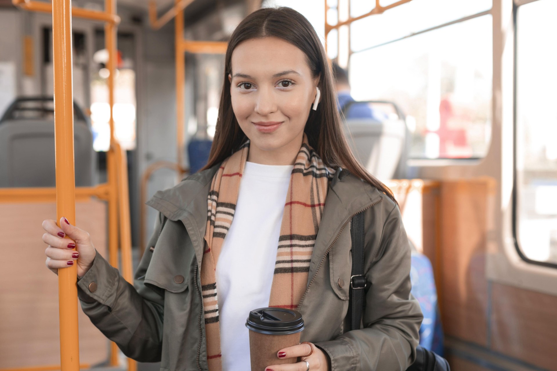 Studentka z kubkiem kawy jedzie tramwajem