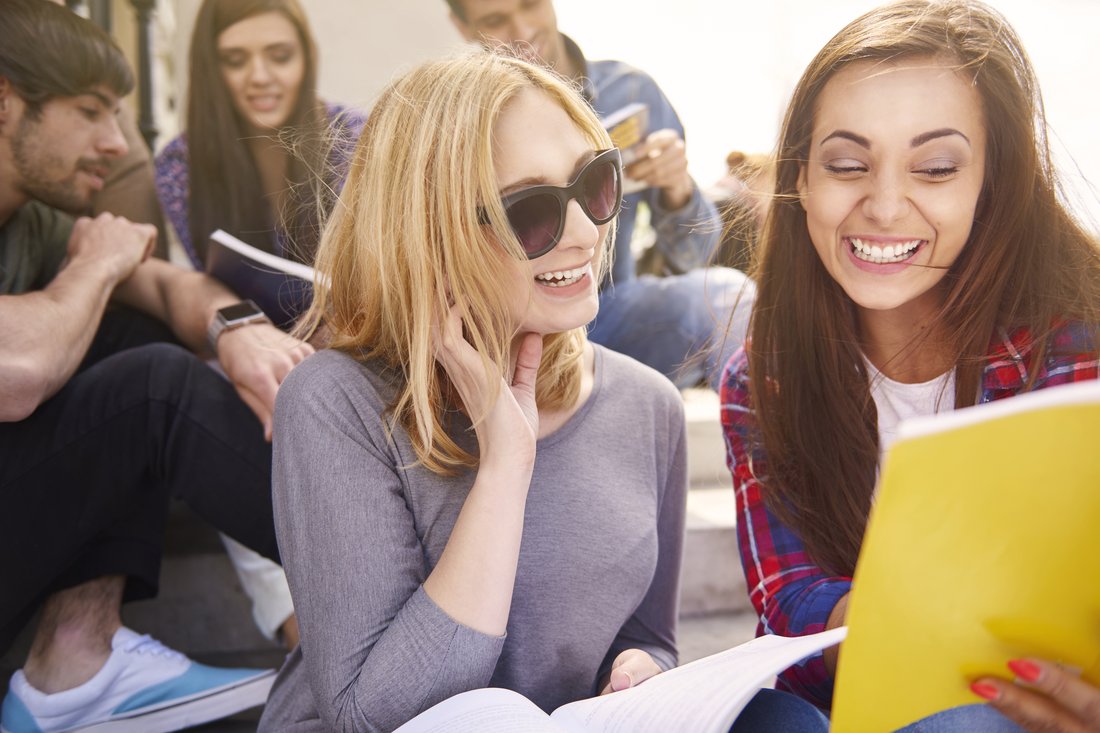 Uśmiechnięte studentki z notatkami na przerwie między zajęciami